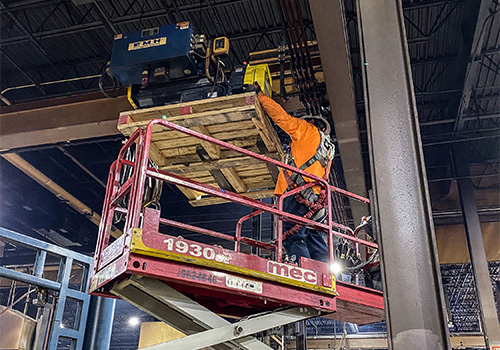 Tri-State Overhead Crane technician performing service on electrical components of a monorail tractor drive.